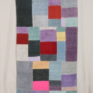 May include: A colorful patchwork rug with squares of various colors, including red, purple, blue, green, yellow, and black. The rug is made of woven fabric and has a textured surface.