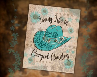 Può includere: Stampa decorativa con un cappello da cowboy turchese con un motivo leopardato. La stampa include il testo "Loving Life in Cowgirl Country" con accenti floreali e stellati su uno sfondo in stile vintage.