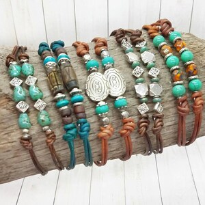 May include: A collection of eight leather bracelets with turquoise and silver beads. The bracelets are tied with a knot at the end and have different bead patterns.