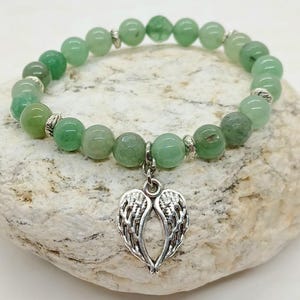 Puede incluir: Una pulsera de cuentas verdes con un dije de alas de &aacute;ngel plateadas. La pulsera presenta cuentas redondas de color verde claro y espaciadores plateados. El dije es una representaci&oacute;n detallada de alas de &aacute;ngel.