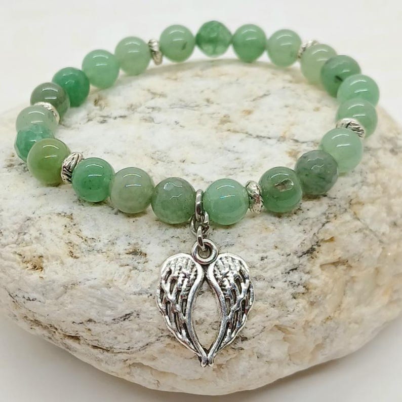 Puede incluir: Una pulsera de cuentas verdes con un dije de alas de &aacute;ngel plateadas. La pulsera presenta cuentas redondas de color verde claro y espaciadores plateados. El dije es una representaci&oacute;n detallada de alas de &aacute;ngel.
