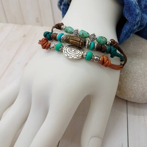 May include: A set of three leather bracelets with turquoise and brown beads, a silver charm, and a wooden bead.