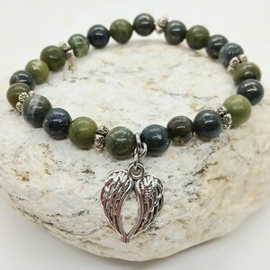 Puede incluir: Una pulsera de cuentas con cuentas de piedras preciosas de color verde oliva y verde azulado oscuro. La pulsera tiene un dije plateado en forma de alas de &aacute;ngel. Las cuentas est&aacute;n ensartadas en un cord&oacute;n el&aacute;stico y est&aacute;n acentuadas con espaciadores plateados.
