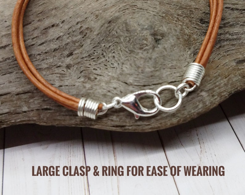 May include: A brown leather cord bracelet with a large silver clasp and ring for ease of wearing.