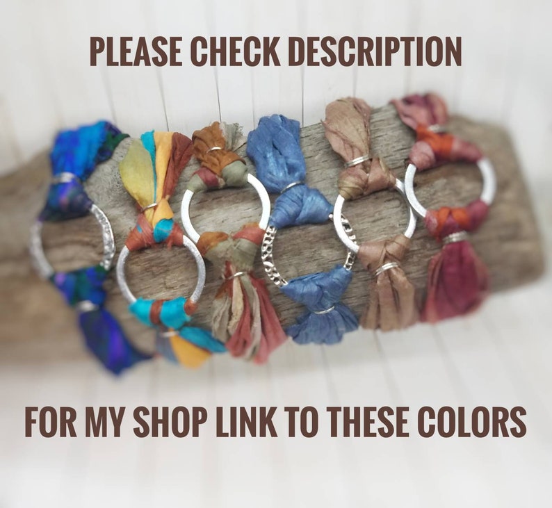 K&ouml;nnte beinhalten: Nahaufnahme von sieben bunten Seidenbandarmb&auml;ndern mit silbernen Ringen. Die Armb&auml;nder sind auf einer Holzoberfl&auml;che angeordnet.  "PLEASE CHECK DESCRIPTION FOR MY SHOP LINK TO THESE COLORS" steht in brauner Schrift unter den Armb&auml;ndern.