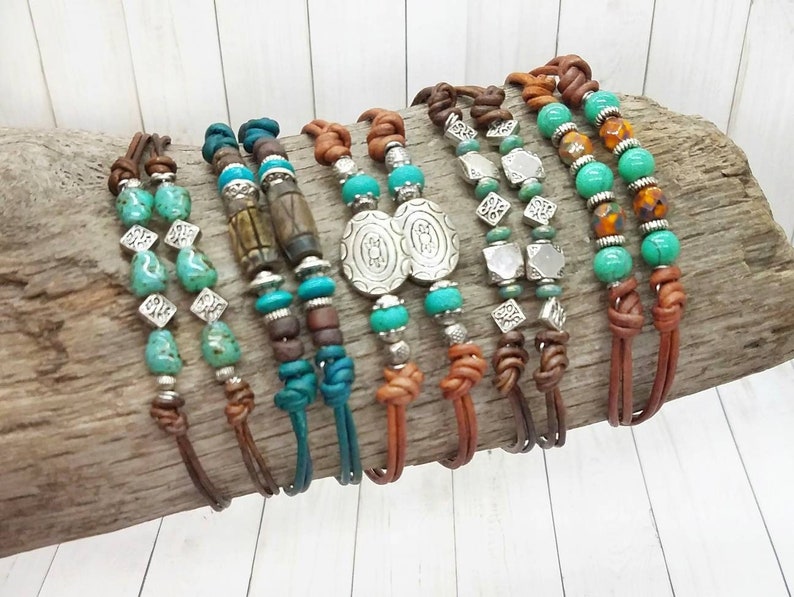 May include: A collection of eight leather bracelets with turquoise and silver beads. The bracelets are tied with a knot at the end and have different bead patterns.