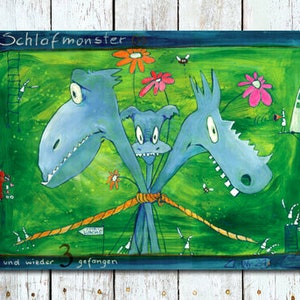 Könnte beinhalten: Eine farbenfrohe Illustration von drei blauen Monstern mit Zähnen, die mit einem Seil zusammengebunden sind, vor einem grünen Hintergrund mit Blumen und einem kleinen Haus. Der Text "Schlafmonster und wieder 3 gefangen" steht am unteren Rand des Bildes.