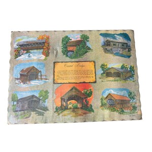 Op de afbeelding: Een vintage textiel met illustraties van overdekte bruggen. De afbeeldingen zijn geplaatst tegen een neutrale achtergrond en omlijst met een geschulpte rand. Het centrale paneel bevat de tekst "Covered Bridges".