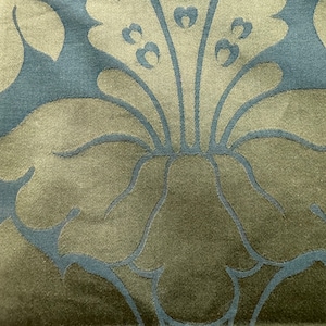 May include: A close-up of a fabric with a repeating pattern of stylized flowers. The flowers are a light blue color on a dark green background.