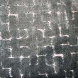 Könnte beinhalten: Nahaufnahme eines strukturierten Stoffes mit einem sich wiederholenden geometrischen Muster. Der Stoff hat ein weiches, samtiges Aussehen mit einer dunkel türkisfarbenen Farbe und einem helleren, fast weißen Muster. Das Design ähnelt einem Ziegel- oder Blocklayout.