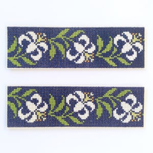 May include: Two blue fabric strips with a white floral pattern. The pattern features white flowers with yellow centers and green leaves.