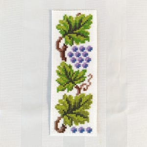 May include: A white fabric bookmark with an embroidered design of green grape leaves and purple grapes.