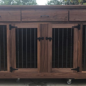 May include: A dark brown wooden dog crate with two doors and three drawers. The crate has black metal bars and black metal hinges. The crate is on wheels.