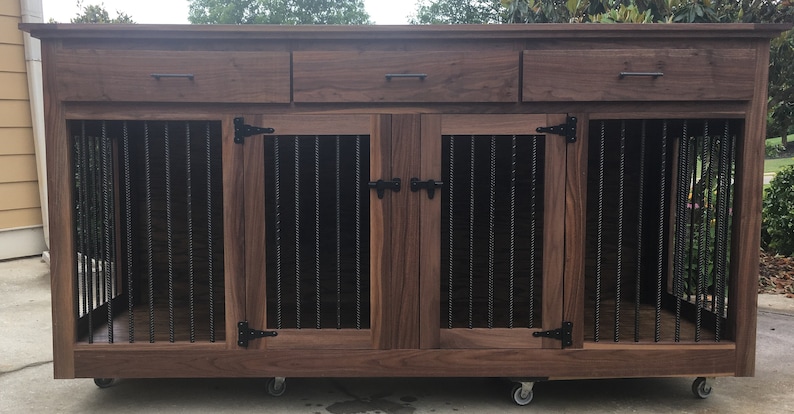 May include: A dark brown wooden dog crate with two doors and three drawers. The crate has black metal bars and black metal hinges. The crate is on wheels.