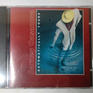 May include: A red and blue CD case with a white figure wearing a yellow hat standing in water. The text on the case reads "Barney Casanova Automatically Yours".