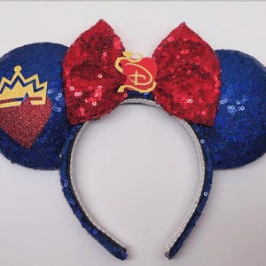 May include: Blue sequined mouse ears with a red sequined bow. The ears feature a gold crown and heart design. The bow has a gold emblem. The headband is blue with a silver trim.