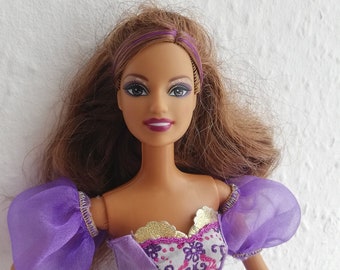 May include: A purple and gold princess doll with brown hair and a purple dress. The doll has a smiling face with brown eyes and purple eyeshadow.