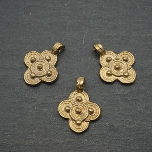 May include: Three antique gold-colored pendants with a four-petal flower design. Each pendant has a loop at the top for hanging. The pendants are made of metal and have a textured surface.
