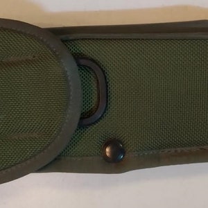 Op de afbeelding: Een groene nylon holster met een zwarte metalen lus en een zwarte drukknoop.