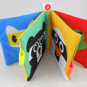 May include: A colorful soft book for babies and toddlers with different animal faces on each page. The book has a bright blue, green, yellow, and red cover with a letter "D" on the front.