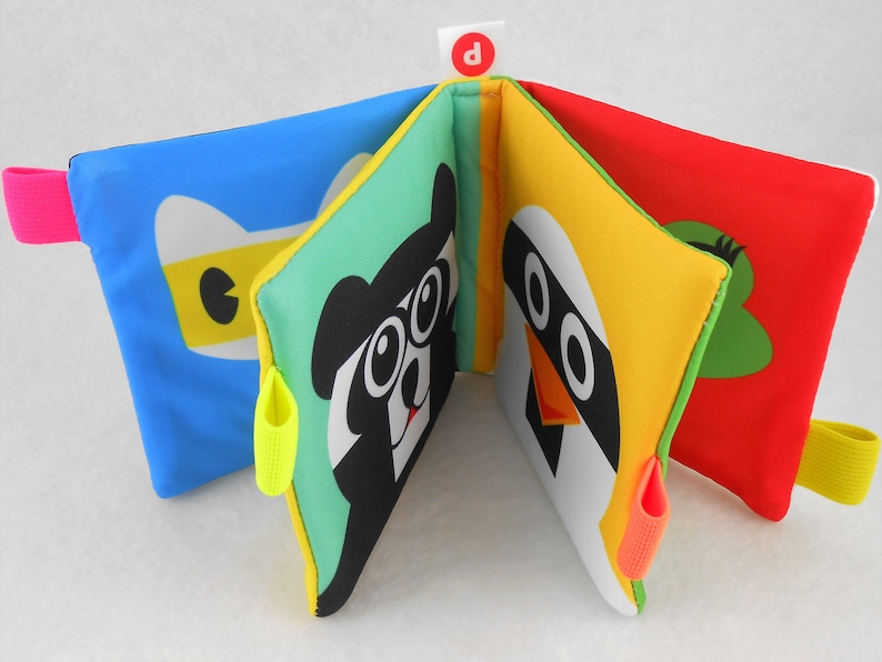 May include: A colorful soft book for babies and toddlers with different animal faces on each page. The book has a bright blue, green, yellow, and red cover with a letter "D" on the front.