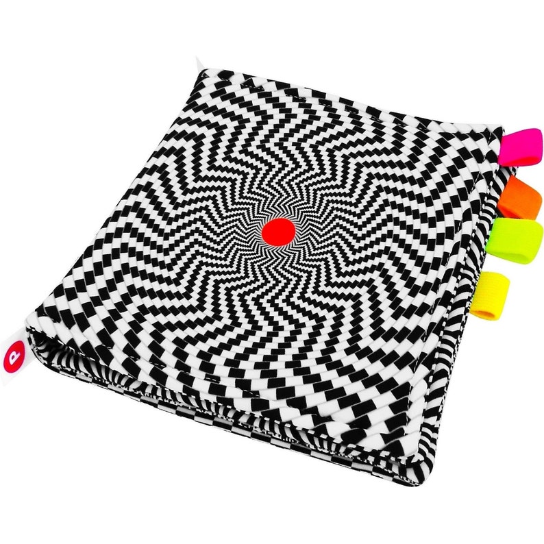 Puede incluir: Libro de tela a cuadros en blanco y negro con un c&iacute;rculo rojo en el centro y etiquetas de tela de colores en el lateral.