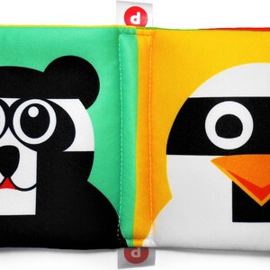 May include: A soft, colorful book for babies with a black and white panda on one side and a white penguin with a black mask on the other side. The book has bright green, yellow, and orange fabric tabs.
