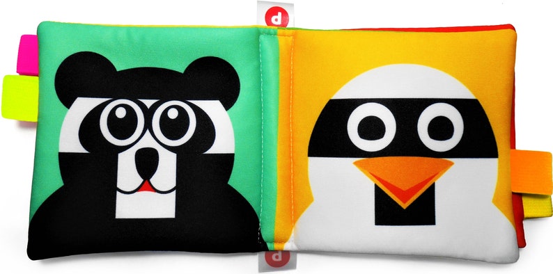May include: A soft, colorful book for babies with a black and white panda on one side and a white penguin with a black mask on the other side. The book has bright green, yellow, and orange fabric tabs.
