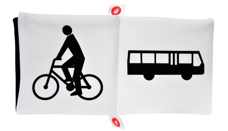 May include: Black and white illustration of a person riding a bicycle and a bus on a white background. The illustration is part of a fabric book.