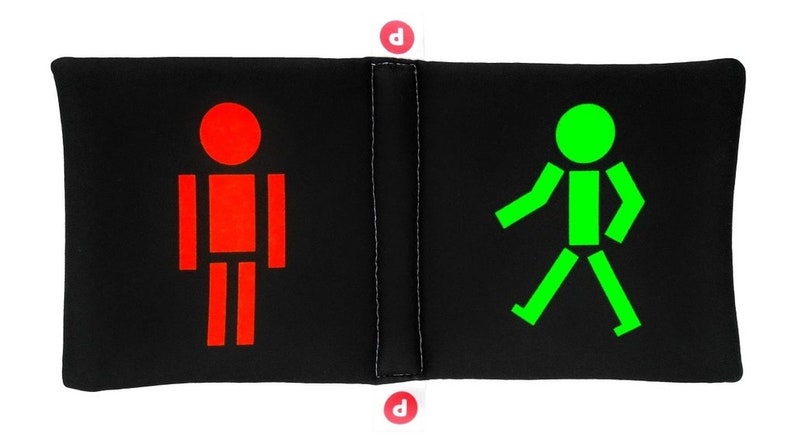 May include: A black and white pillow with a red stick figure on one side and a green stick figure walking on the other side.