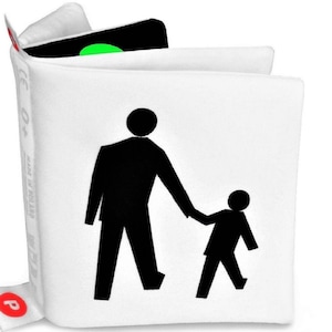 May include: White fabric book with a black silhouette of an adult and child holding hands. The book has a green traffic light on the front cover and the text "CE 04" and "Made in Poland" on the side.