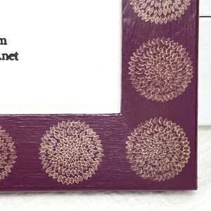 May include: A purple picture frame with a gold floral design. The frame has a white mat and is ready to display a photo or artwork.