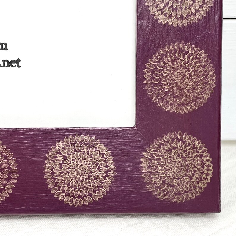 May include: A purple picture frame with a gold floral design. The frame has a white mat and is ready to display a photo or artwork.