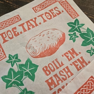 May include: Printed parchment paper with a potato illustration and red text. The text reads "POE.TAY.TOES" and "BOIL 'EM. MASH 'EM." Green ivy leaf illustrations are also printed on the paper.