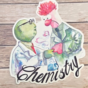 May include: A sticker featuring two Muppet characters in lab coats, one green and one pink, holding a beaker with blue liquid. The word "Chemistry" is written in cursive below the characters.