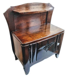 May include: A dark brown wooden nightstand with a small shelf and a cabinet door. The nightstand has a decorative carved design on the cabinet door and a small silver knob. The wood grain is visible.