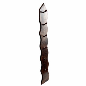 May include: A dark brown wooden wall-mounted coat rack with a wavy design and six hooks.