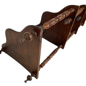 May include: A wooden bookend with three tiers and decorative spindles. The bookend is made of dark brown wood and has a traditional design.