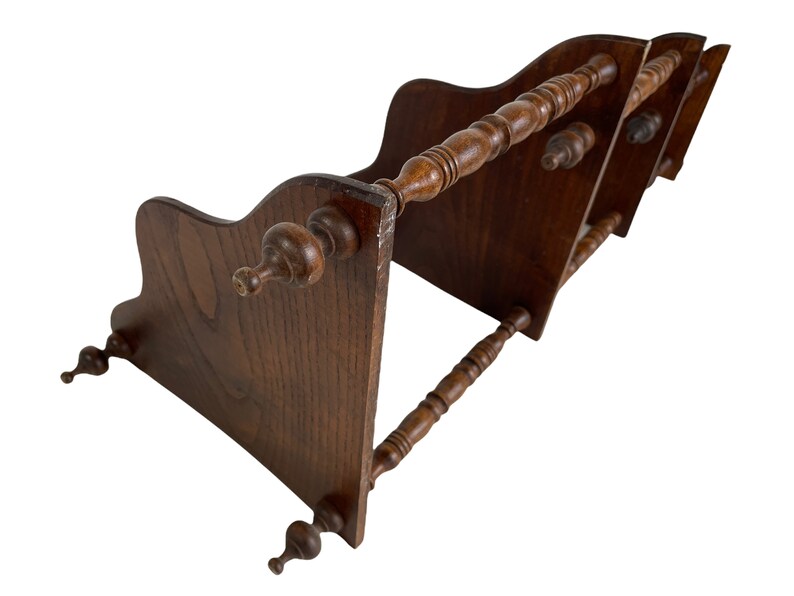 May include: A wooden bookend with three tiers and decorative spindles. The bookend is made of dark brown wood and has a traditional design.