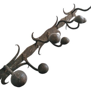 May include: A rustic, wrought iron coat rack with five hooks. Each hook is topped with a round, dark brown ball. The rack has a decorative, scrolled design.
