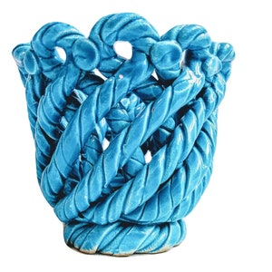 May include: A blue ceramic planter shaped like a woven basket. The planter has a unique design with a textured surface.
