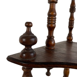 May include: A wooden shelf unit with three tiers, each with a curved edge. The shelf unit has turned wooden legs and finials.