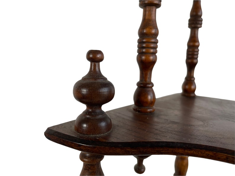 May include: A wooden shelf unit with three tiers, each with a curved edge. The shelf unit has turned wooden legs and finials.