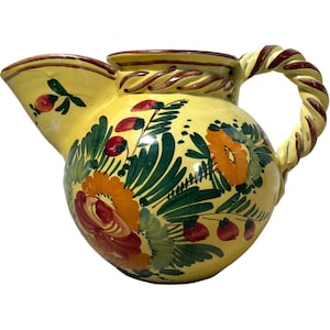 May include: A yellow ceramic pitcher with a twisted handle and floral designs in shades of red, orange, green, and brown.