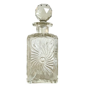 May include: A clear glass decanter with a textured, swirling design and a faceted glass stopper.