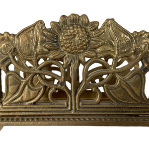 Peut inclure: Porte-serviettes en métal doré avec un motif de tournesol et de feuilles.