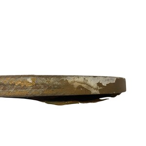 Puede incluir: Primer plano de un objeto redondo y desgastado con base marr&oacute;n y detalles dorados. Los bordes muestran signos de desgaste y pintura descascarillada, revelando capas de color. El objeto parece ser una pieza decorativa.