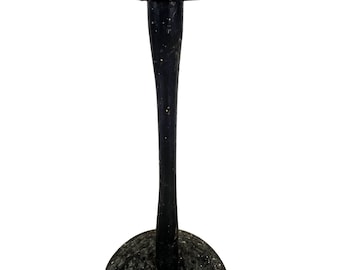 May include: A black wooden hat form with a round top and a wide base. The form is worn and has a speckled finish.