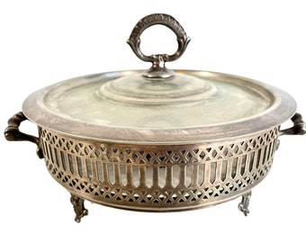 May include: Silver plated serving dish with a glass insert and a lid. The dish has a decorative, openwork design around the edge and three feet.