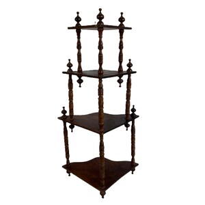 May include: A dark brown wooden corner shelf unit with three tiers. Each tier has a curved edge and is supported by four turned wooden posts with finials.